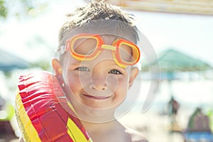 Little boy with rubber ring standing on the beach at the day time. Cute little boy with inflatable ring on the beach