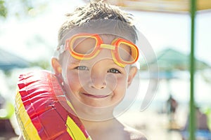 Little boy with rubber ring standing on the beach at the day time. Cute little boy with inflatable ring on the beach