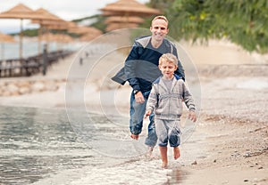 Little boy running with his father at the surf line