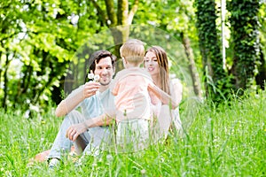 Little boy running over meadow with family in back