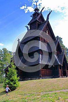 Little boy running and playing in front of the Gol Church, a stave church originally built in Gol city, now in Oslo.