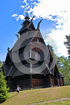 Little boy running and playing in front of the Gol Church, a stave church originally built in Gol city, now in Oslo. photo