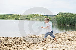 Little boy running on a sand near a pond