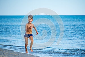 Little boy running at the shore near sea