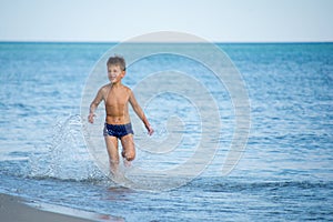 Little boy running at the shore near sea