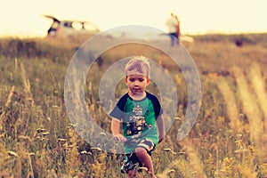 Little boy runs across the field through the grass at sunset