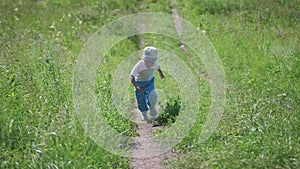 A little boy runs along a narrow path in the forest. Outdoor entertainment. Hot summer day