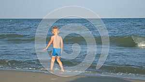 A little boy runs away from the waves on the beach sea.