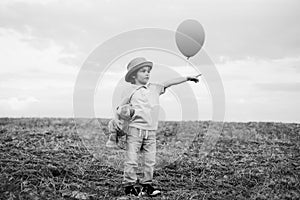 Little boy on the rural road between the colored groung field pointing at a copyspace. The cute boy in the nature