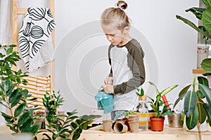 Little boy with sad face watering plants with the can as part of his chores