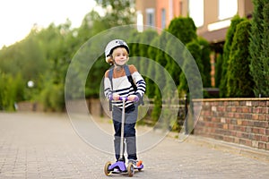 Little boy in safety helmet is riding scooter to school. Quality protect equipment for safety kids on street of city. Back to