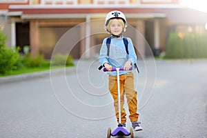 Little boy in safety helmet riding scooter to school. Quality protect equipments for safety kids on street of city. Back to school