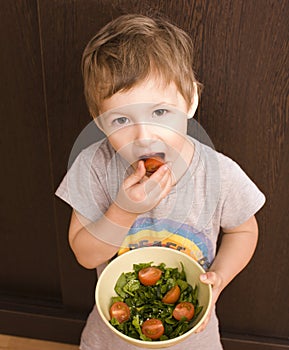 Little boy with salad and tomato