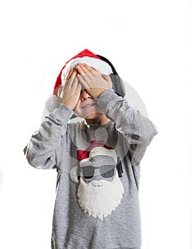 Little boy in Santa Claus hat closed eyes with hands in anticipation of a Christmas miracle and a gift