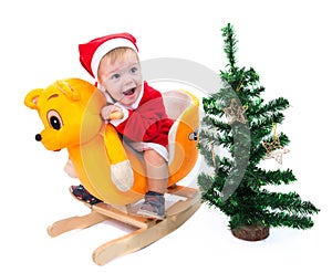 Little boy in Santa Claus suit riding a toy cat