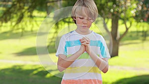 Little boy saying his prayers in the park
