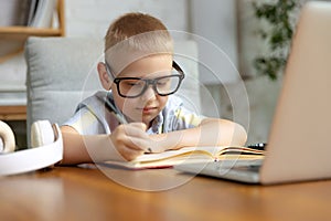 Little boy, school age kid doing homework, using laptop at home interior. Education, childhood, people, homework and