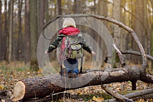 Little boy scout with backpack and rope during hiking in autumn forest