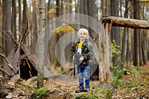 Little boy scout with binoculars during hiking in autumn forest. Child is looking through a binoculars