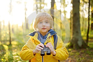 Little boy scout with binoculars during hiking in autumn forest. Child is looking with binoculars. Adventure, scouting and hiking