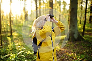 Little boy scout with binoculars during hiking in autumn forest. Child is looking with binoculars. Concepts of adventure, scouting