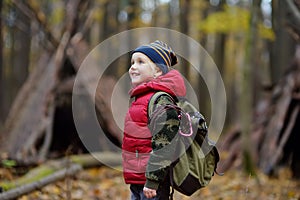 Little boy scout during hiking in autumn forest. Teepee hut on background