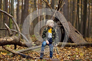 Little boy scout with spyglass during hiking in autumn forest. Child is looking through a spyglass