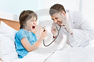Little boy screaming into doctor`s stethoscope