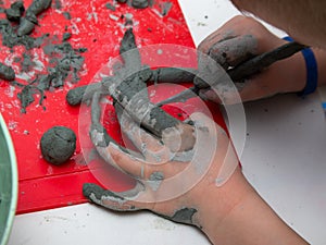 Little boy sculpts from clay with interest. Pottery workshop for kids, raw clay, sculpting tools, glazing and painting clay.