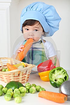 Little boy with serious face in kitchen apron and photo