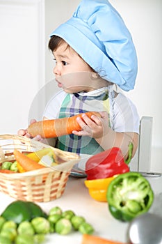 Little boy with serious face in kitchen apron and photo