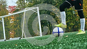 Little boy in shorts and trainers with his foot resting on top of a soccer ball on green grass.