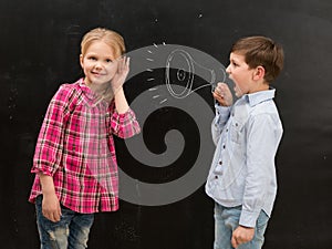 Little boy shouting in drawn mouthpiece and girl covering ears with her hands