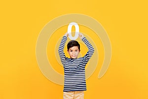 Little boy showing number zero on yellow background