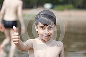 A little boy shows a thumbs up like in the middle of frozen water droplets in the air