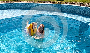 Little boy with sister in the pool during vacation