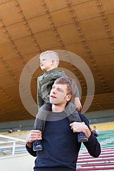 Little boy sit on father's shoulders