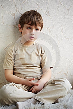 Little boy sits alone on fleecy white rug