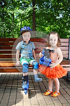 Little boy sits on bench and girl helps to him in