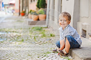 Little boy sits on the doorstep on a city street