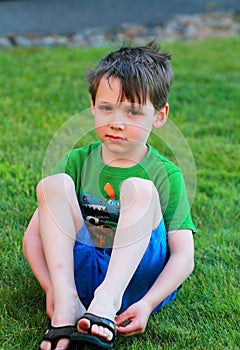 Little boy sits in the grass.