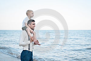 Little boy sits on shoulders of his father. Young handsome man and his son. Older and younger brothers