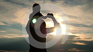 A little boy sits on the shoulders of mom In a Beautiful Summer Day At Sunset. Silhouette of a happy mother holding his