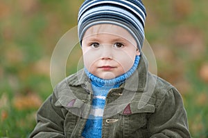Little boy sitting on the autumn grass