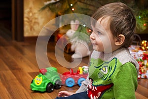 A little boy sitting on the background of the Christmas tree with gifts. Concept Christmas