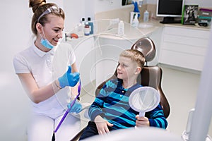 Little boy sitting in dentist chair and speek with dentist photo