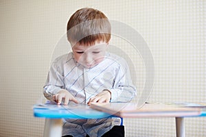 Little boy sitting at the desk and reading a book