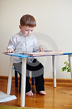 Little boy sitting at the desk and reading a book