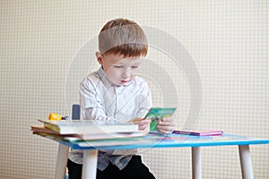 Little boy sitting at the desk and reading a book