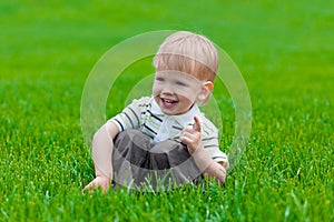 Little boy sitting and dreaming in green grass